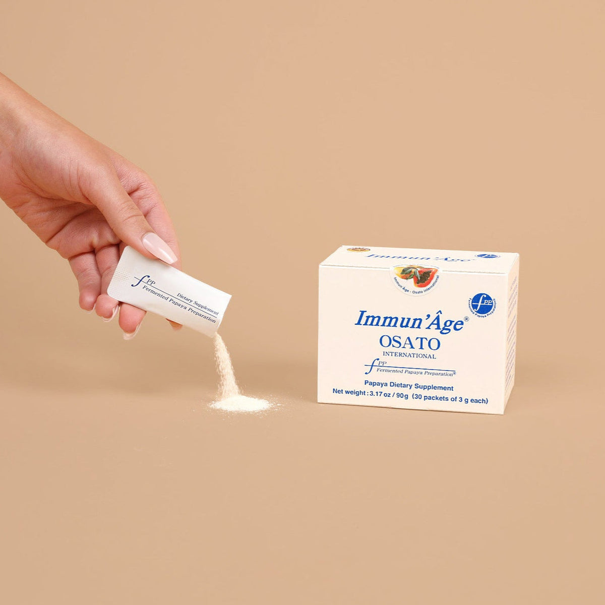 Hand holding a container of Immun'Age Osato powder with the packaging on a beige background
